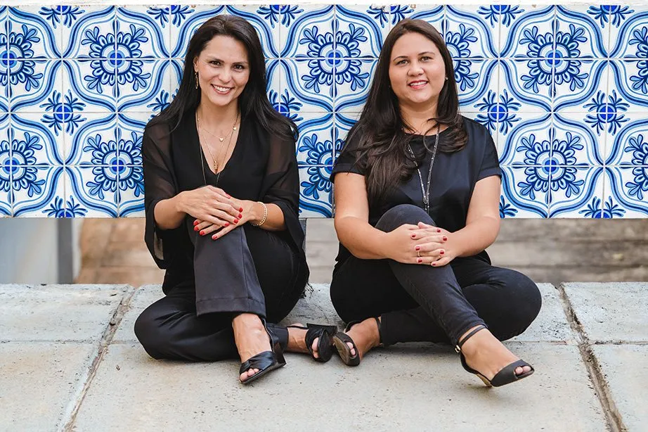 As sócias Eveline Freitas e Rosane Andrade sentadas diante de uma parede de azulejos azuis e brancos